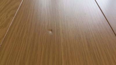 フローリング表面に硬いものを落としてできたような、白っぽく凹んだ傷のアップ