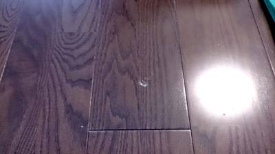 補修前のウォルナット色フローリングのヘコミ傷の写真
