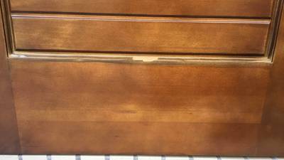 木製玄関ドアの下部モール部分が剥がれて下地が見えている状態