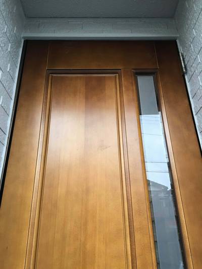 紫外線や雨風の影響でクリア塗装が白く劣化し、剥がれ落ちている木製ドアの下部