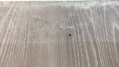 フローリングの表面にドリルで開けたようなビス穴があり、周囲に木の粉が付着している状態