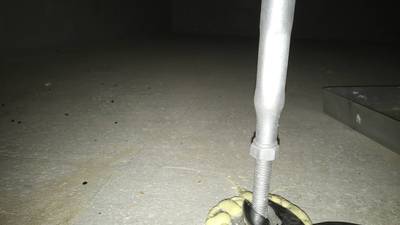 コンクリート土間に接する鋼製束の下部に接着剤を充填し、レンチで高さを微調整して固定している様子