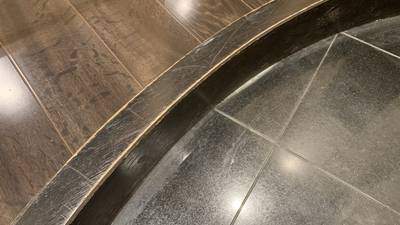 カーブした玄関の上がり框の角や表面に無数の擦り傷があり、塗装が剥がれて下地が白く見えている状態