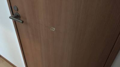 物をぶつけて凹みと線傷ができた木目調ドア