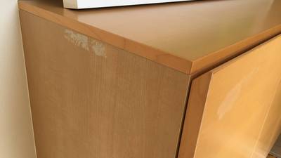 粘着テープで表面が剥がれてしまった下駄箱の写真