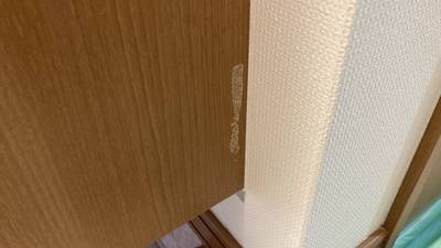 玄関の下駄箱側面の木目調パネル表面が剥がれて下地が見えている状態