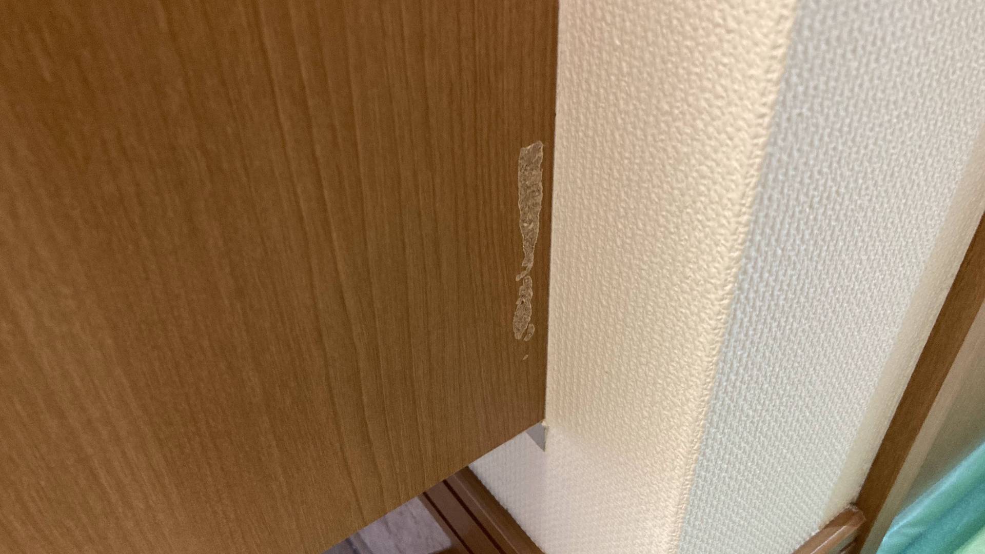 玄関の下駄箱側面の木目調パネル表面が剥がれて下地が見えている状態